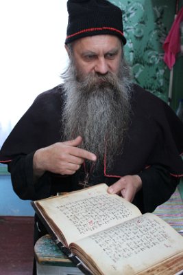 Mužský klášter Veivodina-Mnich ukazuje bibli ze 16-století